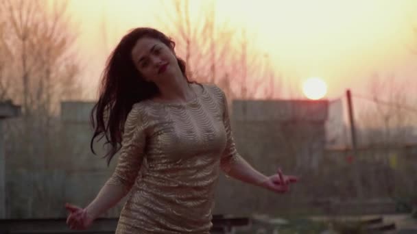 Красивая брюнетка танцует на закате в металлической конструкции — стоковое видео