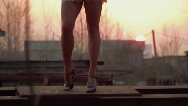 Elegante donna in abito da ballo al tramonto sullo sfondo in costruzione di metallo — Video Stock