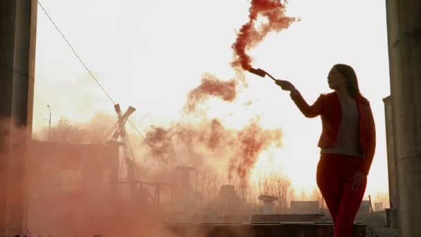 Красивая девушка танцует с красным дымом на фоне заката — стоковое видео