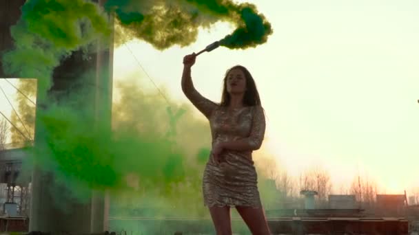 Mulher sexy em vestido dourado dançando com fumaça verde sob ponte abandonada — Vídeo de Stock