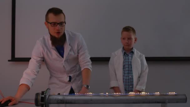 Лаборант с мальчиком проводит эксперимент с огненным громкоговорителем — стоковое видео
