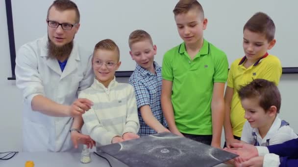 Laboratorium-assistent toont jongens dansen zand op chladni plaat — Stockvideo