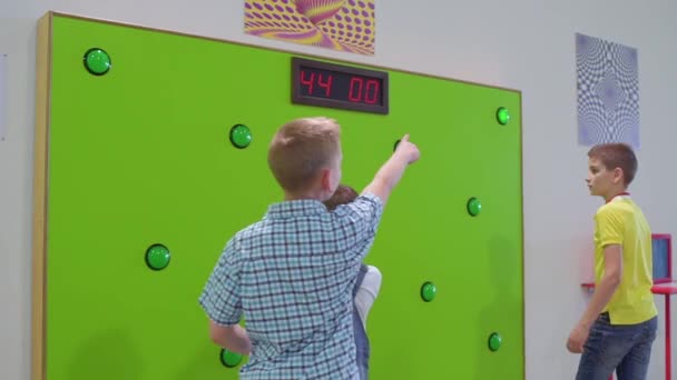 Three boys play a game of reaction speed in scientific museum — Stock Video