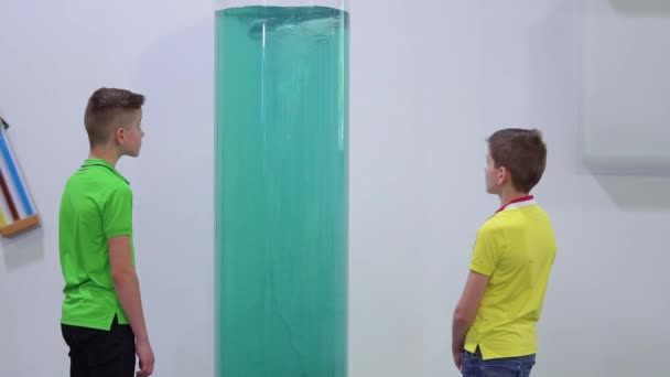 Два мальчика смотрят на искусственный водоворот в музее поп-науки — стоковое видео
