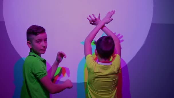 Two cute boys shows thumbs up, colorful shadows on the wall — Stock Video