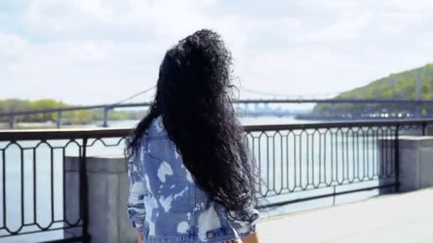 제방에서 아름 다운 곱슬 갈색 머리 산책 — 비디오