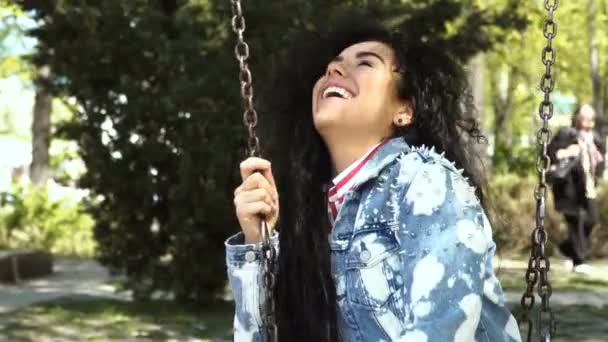 Happy brunette swings on swing in park — Stock Video