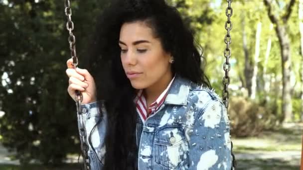 Jolie fille en jean veste balançoire sur swing dans le parc — Video