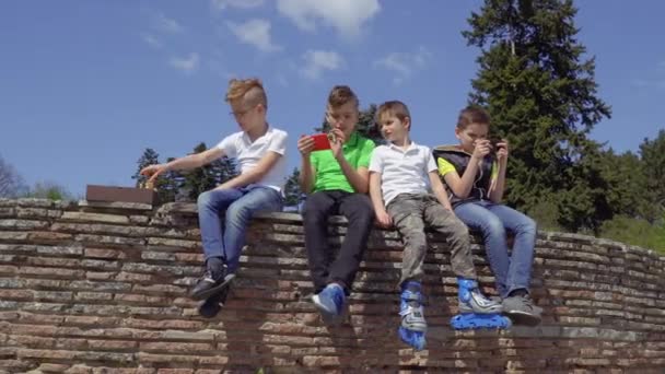 Four boys sits at concrete wall and relaxing — Stock Video