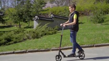 Çok güzel çocuk yaz Park tekme scooter sürme