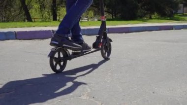 Park asfalt yol boyunca tekme scooter sürme genç