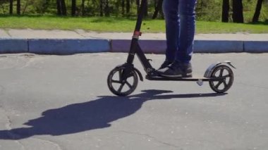 Oğlum giyen kot pantolon ve spor ayakkabılar üzerinde sürme scooter yolda tekme