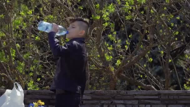 Підліток п'є воду в парку — стокове відео