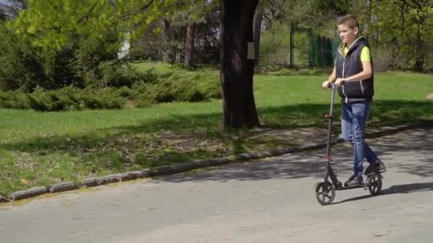 Adolescentes paseos en patinete scooter en el parque — Vídeos de Stock