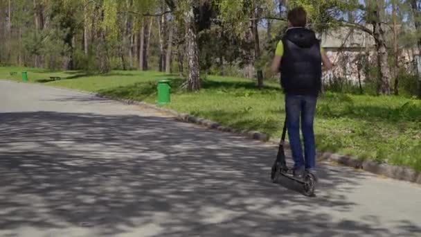 Niño montando en patinete scooter en el parque — Vídeos de Stock