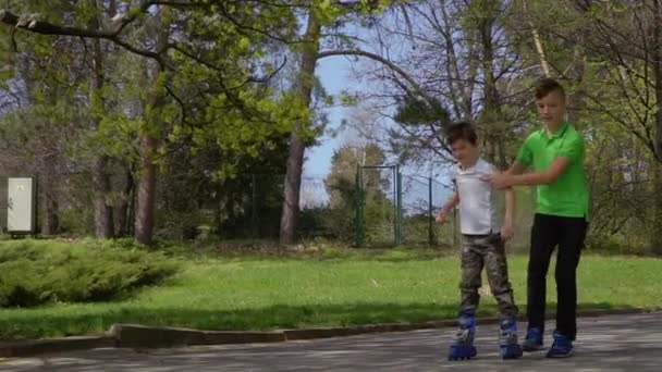 Hermano ayudar a su hermano menor a aprender a montar en patines — Vídeos de Stock