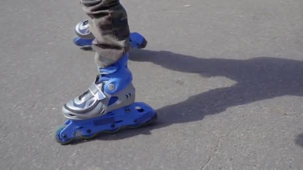 Menino em patins rolo azul equitação no parque — Vídeo de Stock