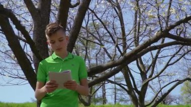 Sevimli çocuk defter tutan ağaç parkta üzerinde eğilir