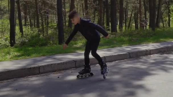 Elegante adolescente in giacca di pelle cavalcando sui pattini a rotelle nel parco estivo — Video Stock