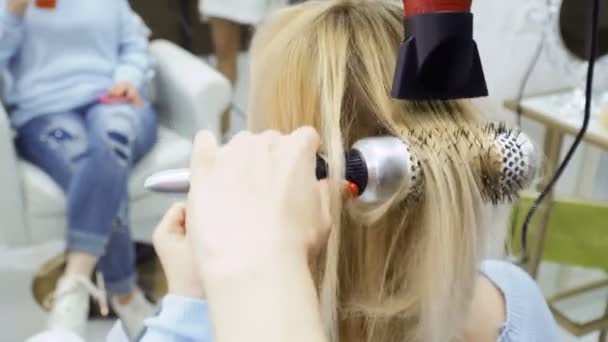 Cabeleireiro seca o cabelo feminino com secador de cabelo e escova — Vídeo de Stock