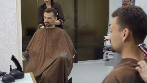 Cabeleireiro corta cabelo de homem bonito com lâmina elétrica — Vídeo de Stock