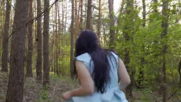 Charmiga brunett i blå klänning promenader i skogen med apple i hand — Stockvideo