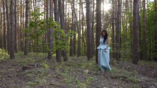 Vacker kvinna i långa blå klänning går i sommar skog — Stockvideo