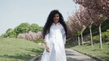 Güzel kıvırcık kadın yürümek yavaş çekimde çiçek açan Park