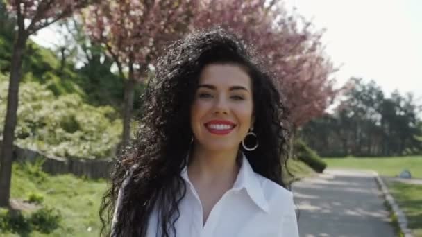 Счастливая красивая женщина гуляет в цветущем парке, замедляя движение — стоковое видео