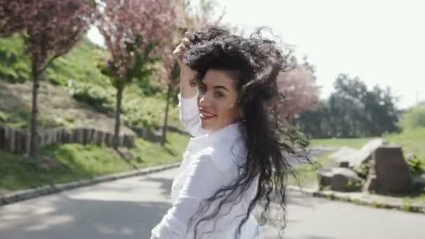 Prachtige volwassen vrouw lopen in bloeiende park in slow motion — Stockvideo