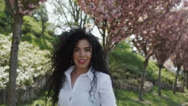 Великолепная женщина гуляет в цветущем парке в замедленной съемке — стоковое видео