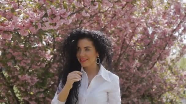 Brunett promenad nära sakura i slow motion — Stockvideo