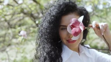 Genç kadın gülümseme Manolya elinde tutan kamera için