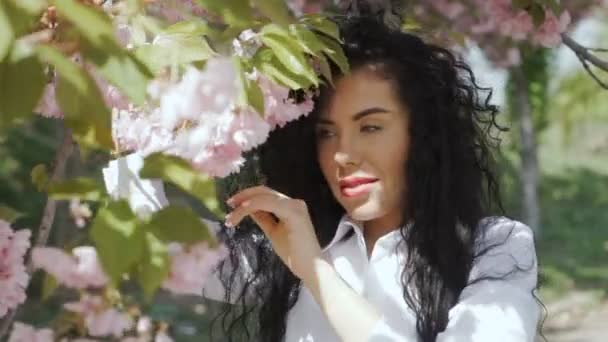Гарненька брюнетка пахне квітами сакура — стокове відео