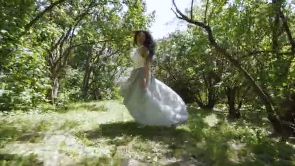 Belle brune en robe bleue courir à travers un jardin, au ralenti — Video