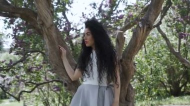 Güzel esmer tree yakınındaki kamera için poz