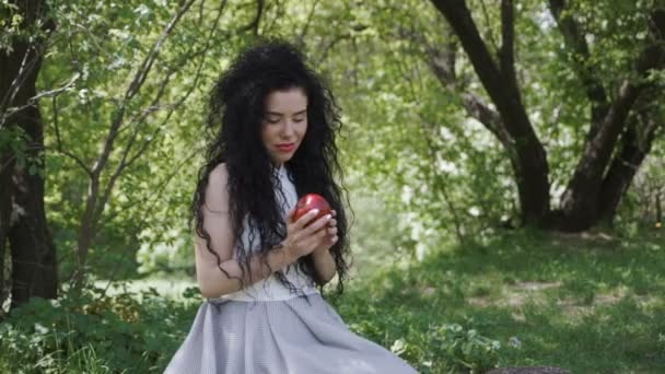 Hermosa mujer en vestido azul disfrutar de un olor a manzana roja fresca — Vídeo de stock