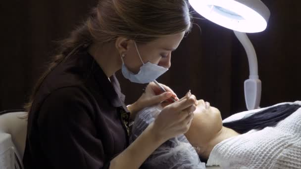 Esteticista faz o procedimento da extensão de pestana no salão de beleza — Vídeo de Stock