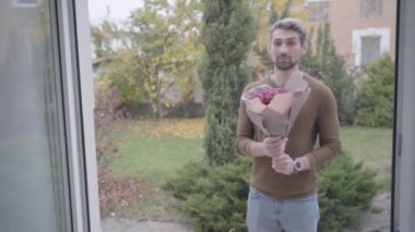 Kapı açılıyor ve verandada elinde mor güller olan yakışıklı bir adam bekliyor. Güzel beyaz kadın çiçek almayı reddediyor, kocasını ya da erkek arkadaşını uzaklaştırıyor ve kıyafet kapısını açıyor..