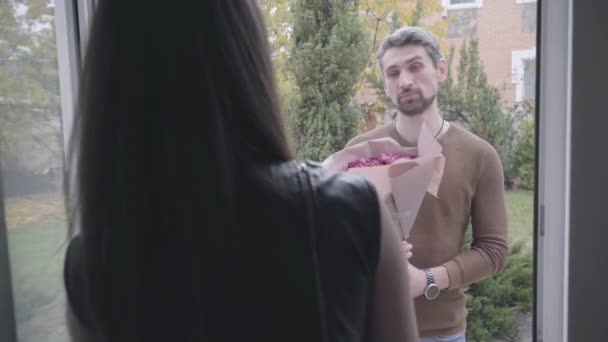 Beau jeune homme avec un bouquet de roses violettes debout à la véranda. Belle femme caucasienne refusant de prendre des fleurs, repoussant son mari ou son petit ami et la porte des vêtements. Problèmes, culpabilité . — Video