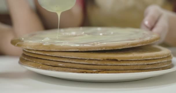 Extrême gros plan de gâteau cuit enduit de lait condensé. Mains blanches féminines mettant une autre couche vers le haut. Douce boulangerie dans l'assiette. Cinéma 4k séquences ProRes HQ . — Video