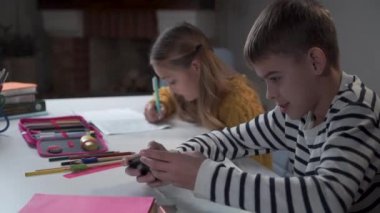 Okuldaki akıllı telefonlarda oyun oynayan yaramaz beyaz bir öğrencinin portresi. Arka planda ona bağıran çalışkan kız şok oldu. Kamera sağdan sola hareket ediyor.