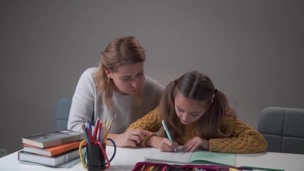 Atraktivní bělošská matka dává pět svým roztomilým chytrým dcerám. Žena pomáhá inteligentní školačce s domácími úkoly. koncept vzdělávání, základní škola, domácí vzdělávání. — Stock video