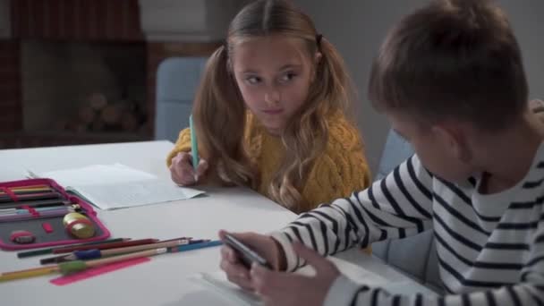 Porträtt av en chockad vit skolflicka som tittar på sin klasskamrat som spelar spel på smarttelefon i skolan. Närbild av en flitig flicka och stygg pojke på lektionerna. Olika beteenden, utbildning. — Stockvideo