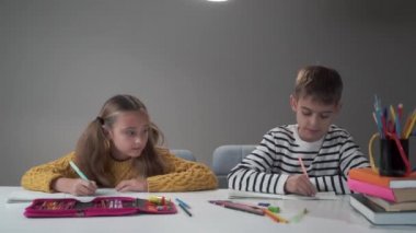 Kafkasyalı iki öğrencinin not defterlerini kaldırıp gülümsemesi. Kız ve erkek, okul zili çaldıktan sonra mutlu oldular. Eğitim süreci.