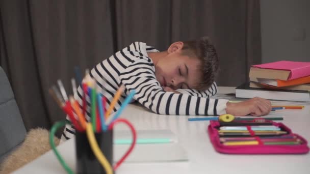 Cara de cerca de un niño caucásico durmiendo en la mesa. Colegial cansado después de hacer la tarea en casa. Lindo niño en chaqueta a rayas agotado después de estudiar . — Vídeo de stock