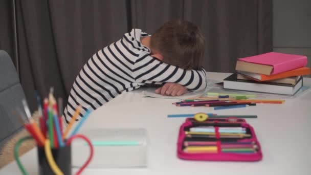Retrato de un chico caucásico durmiendo en su libro de ejercicios. Colegial cansado después de hacer la tarea en casa. Lindo niño con chaqueta a rayas agotado después de estudiar. Cámara moviéndose de derecha a izquierda . — Vídeo de stock