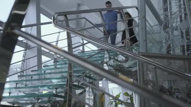 Веселый белый взрослый мужчина и маленькая девочка спускаются по современной лестнице в аэропорту. Отец и дочь отправляются в зону отправления или прибытия. Туризм, путешествия, путешествия . — стоковое видео