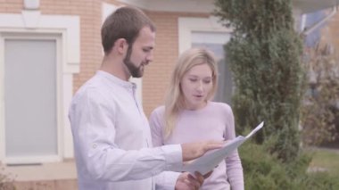 Tatmin olmayan beyaz kadın müşteri projeyi tasarımcıyla tartışıyor. Sakallı mimar müşteriye çizimleri açıklıyor. Profesyonel meslek, yaratıcılık, ev tasarımı.