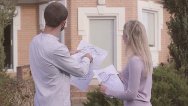 수염을 기른 코카서스 건축가는 집 앞에서 그 의보 조자에게 젊은 금발의 여인에게 건축 도면을 주면서 프로젝트를 설명한다. 직업적 인 직원들에게 일의 비밀을 가르치는 일. — 비디오